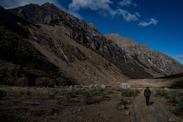 Hiker walking in a valley surrounded by mountains in the Peruvian Andes. 