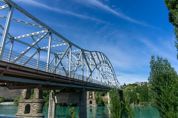 Historic bridge ruins over the Clutha River in Alexandra, New Zealand. Surrounded by the striking blue waters and lush greenery of Otago, nature lovers photographers exploring South Island