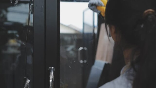 Cleanliness asian young woman working chore cleaning on table at home, hand wearing glove using rag rub remove dust with spray bottle. Household hygiene clean up, cleaner, equipment tool for cleaning
