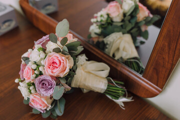 A bouquet of flowers is displayed in front of a mirror. The flowers are pink and white, and they are arranged in a vase. The mirror reflects the bouquet, creating a sense of depth and dimension