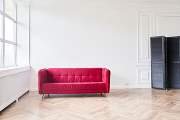 The modern living room has a red sofa, parquet floor with brown tones and a smooth polished surface. With space to copy. High quality photo