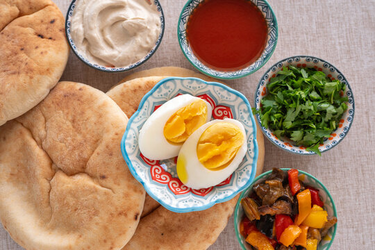 Boiled eggs for preparation traditional Israeli Sabich Pita on the background of ingredients for it..