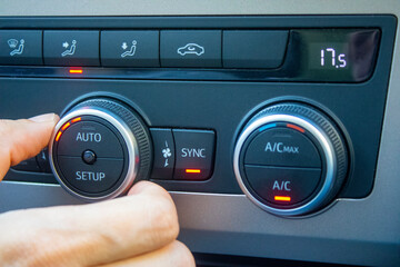 Set up air conditioner in the car. Hand turns air conditioner ring. Display indicates 17.5 degree celsius temperature inside the car. Cooling air in the car