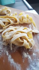 Fresh homemade pasta noodles on a wooden board with flour.