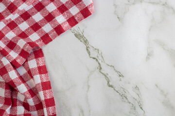 Red and white checked napkin on the left side, on a marble surface