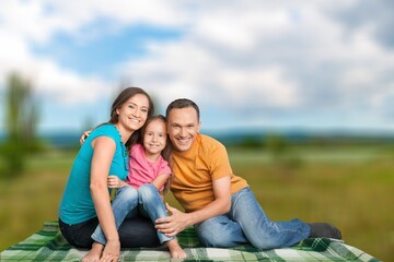 Fototapeta premium Cheerful young family sitting on the park.