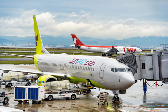 Osaka, Japan - 05.13.2024: Jin Air Boeing 737-8Q8 airplane or aircraft at the jet bridge or passenger boarding bridge on the runway at Kansai International airport