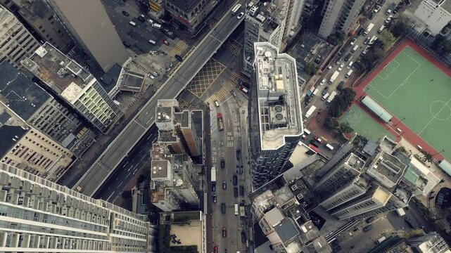 City, buildings and cars on highway from drone in Hong Kong with traffic or travel in development. Cityscape, road and infrastructure downtown with architecture, grid and rooftop of skyscraper