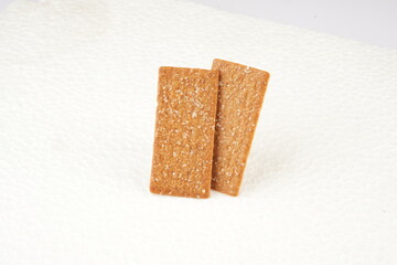 the image of the thin, rectangular coffee biscuit with a sugar coating on a white surface.