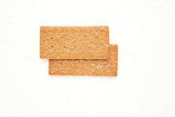 the image of the thin, rectangular coffee biscuit with a sugar coating on a white surface.