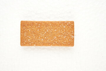 the image of the thin, rectangular coffee biscuit with a sugar coating on a white surface.