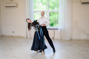 Pair of professional dancers, man and woman, perform at sports competition, dance tango in...