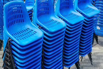 Stacked rows of blue plastic chairs with metal frames for outdoor events on town square