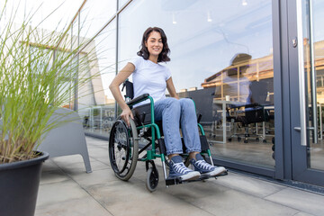 Young dark-haired woman on a wheelchair near the office building