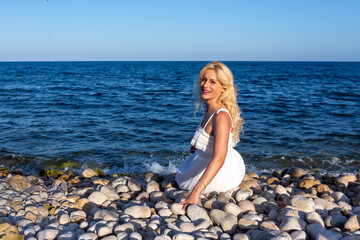 Blonde Woman Relaxing on Rocky Beach Shore