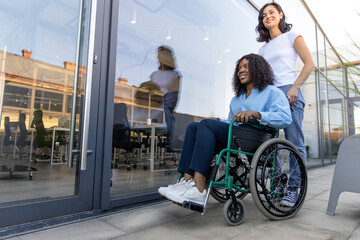 Young woman carrying a wheelchair with a disabled african american woman