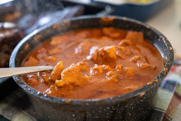 A close-up of a steaming bowl of chicken tikka masala, featuring tender chicken pieces in a rich, creamy tomato-based sauce.