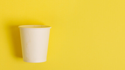 Disposable paper cup for coffee and tea on a bright orange background.