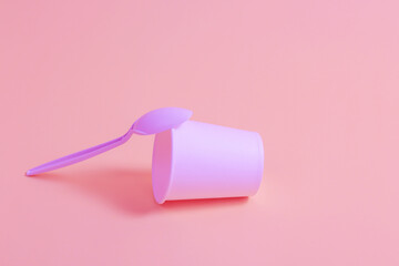 Disposable tableware on a pink background.