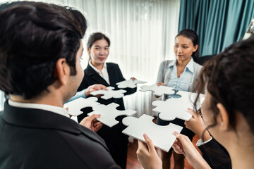 Multiethnic business people holding jigsaw pieces and merge them together as effective solution solving teamwork, shared vision and common goal combining diverse talent. Meticulous