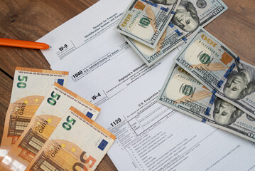 Tax forms with U.S. dollars and euros on a wooden table, featuring tax documents and currency. Financial concept for tax filing and preparation. Accounting and tax season essentials 