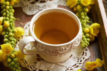 A white ceramic cup of herbal tea with fresh blooming mullein or Verbascum plant