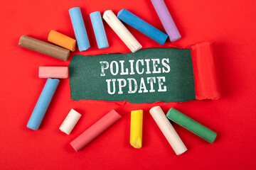 Policies Update. Text under torn red paper on a green chalkboard