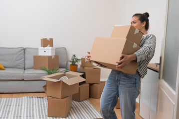 Woman holds heavy boxes with personal items standing in bright premise of new accommodation parcels...