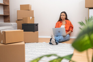 Young female thinks about moving to new flat collecting all necessary things with household items in cardboard boxes for reliable transportation to another city