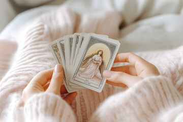 Close-Up of Woman’s Hands Shuffling Tarot Deck with Angel Card on Light Pink Sweater

