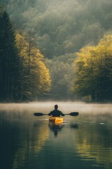 A man kayaking in still lake water with forest and fog