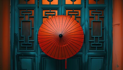 A red paper umbrella hanging in front of an orange door with blue grilles