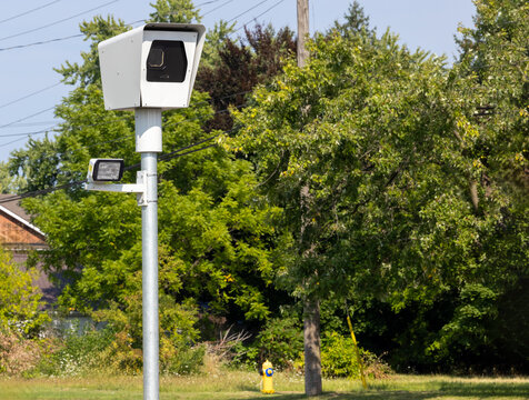 A road side pole mounted speed camera with trees in the background