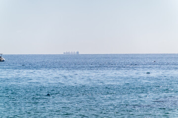Calm blue sea with the silhouette of a large ship on the horizon