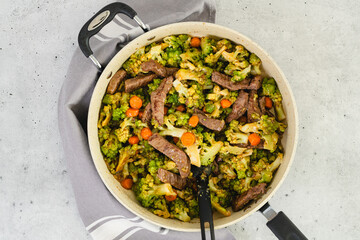 Beef and broccoli with stir fry sauce recipe. Delicious meal cooked in a frying pan, close-up on kitchen table, flat lay