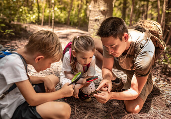 parent and children hiking exploring  forest with magnifying glass learning about nature 