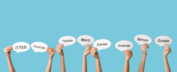 Hands holding speech bubbles with text THANK YOU in different languages on blue background