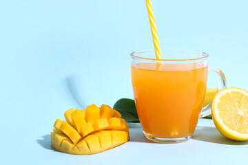 Glass of fresh mango smoothie on blue background, closeup