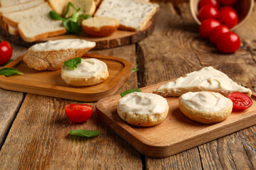 Boards of tasty croutons and toast with cream cheese on wooden background
