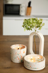Hydrangea flowers and burning candles on table in light kitchen, closeup