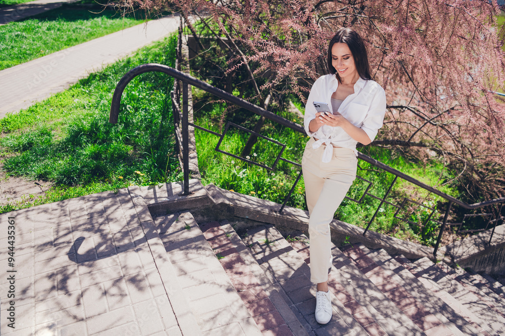 Sticker Full length photo of pretty young good mood girl stand stairs hold device wear white clothes walk outside urban city park