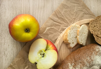 Freshly sliced ​​bread and red apple on wooden platter. Cozy home kitchen for menu design