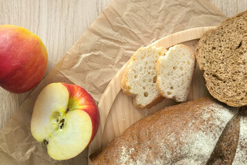 Freshly sliced ​​bread and red apple on wooden platter. Cozy home kitchen for menu design