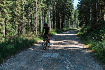 Fototapeta premium Man Cyclist in Cycling Kit Riding Gravel Bike on Scenic Forest Road
