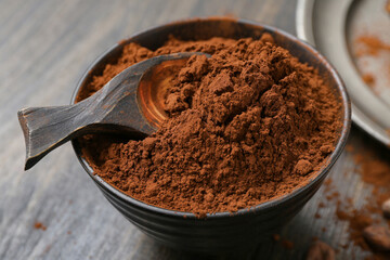 Bowl with cocoa powder on wooden background