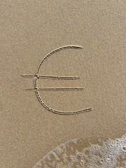 On the beach in the sand is carved a euro symbol