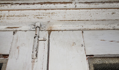 Close-up view of a vintage wooden door hinge and frame showing weathered paint and rustic details in an old building