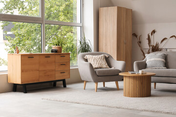 Light living room with grey sofa, armchair and wooden chest of drawers