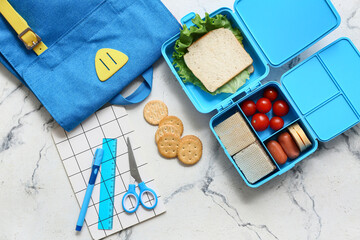 Lunch box with tasty food and school backpack with stationery on white background