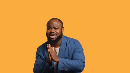 African american man putting hands together in begging gesture, making wish, isolated over yellow...